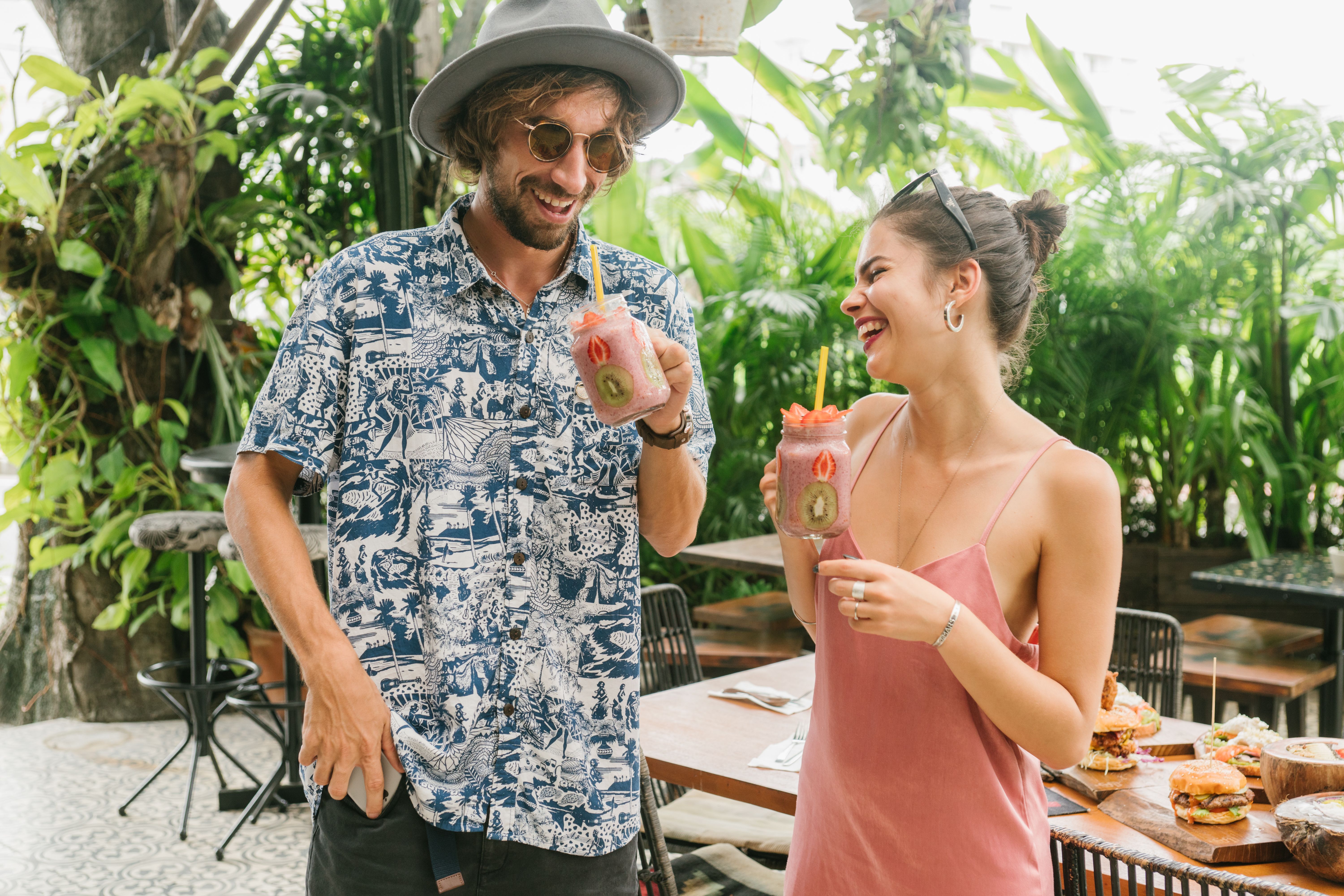 Un couple rit autour de jus de fruits à la terrasse d’un café