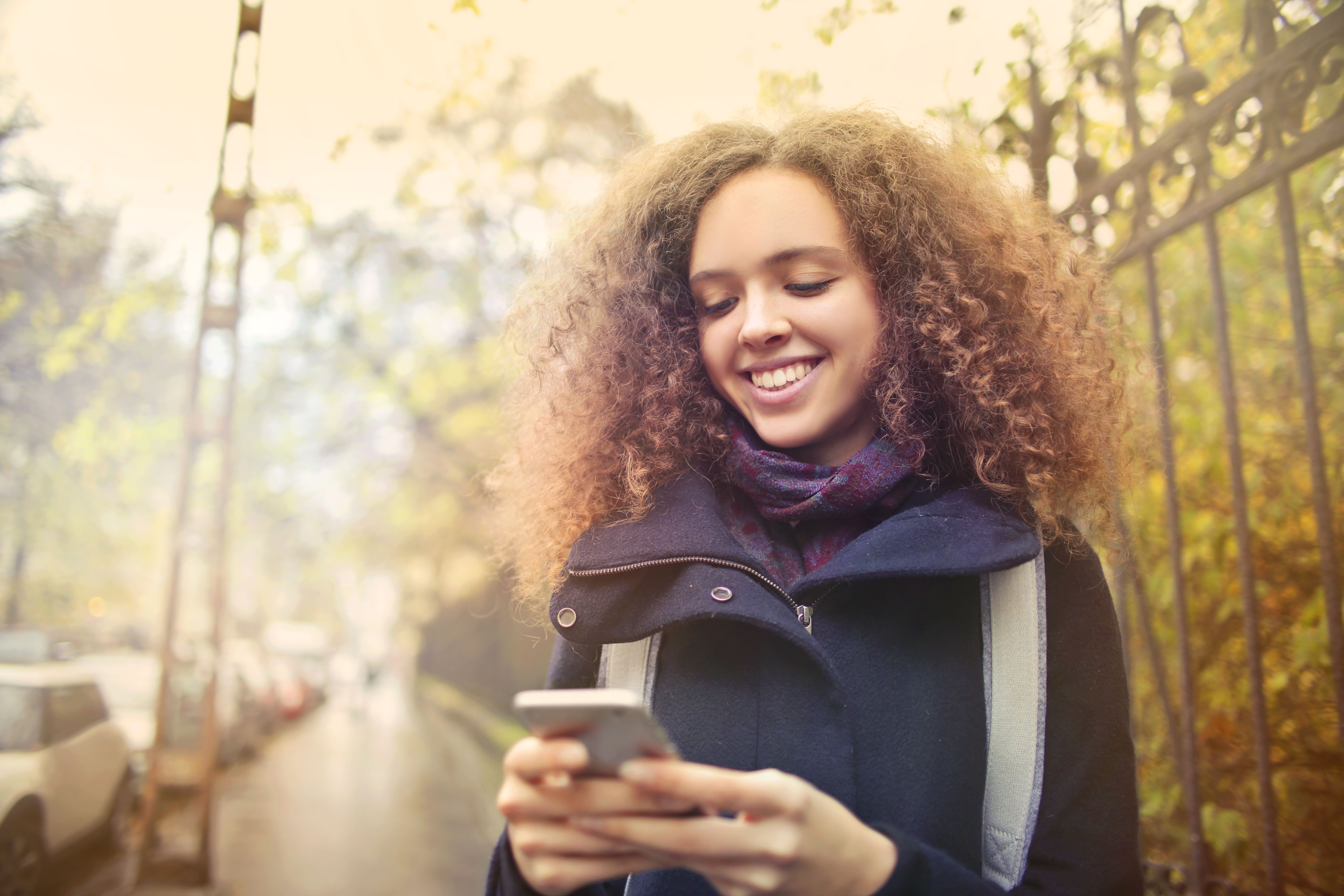 Une jeune femme sourit en écrivant sur son téléphone