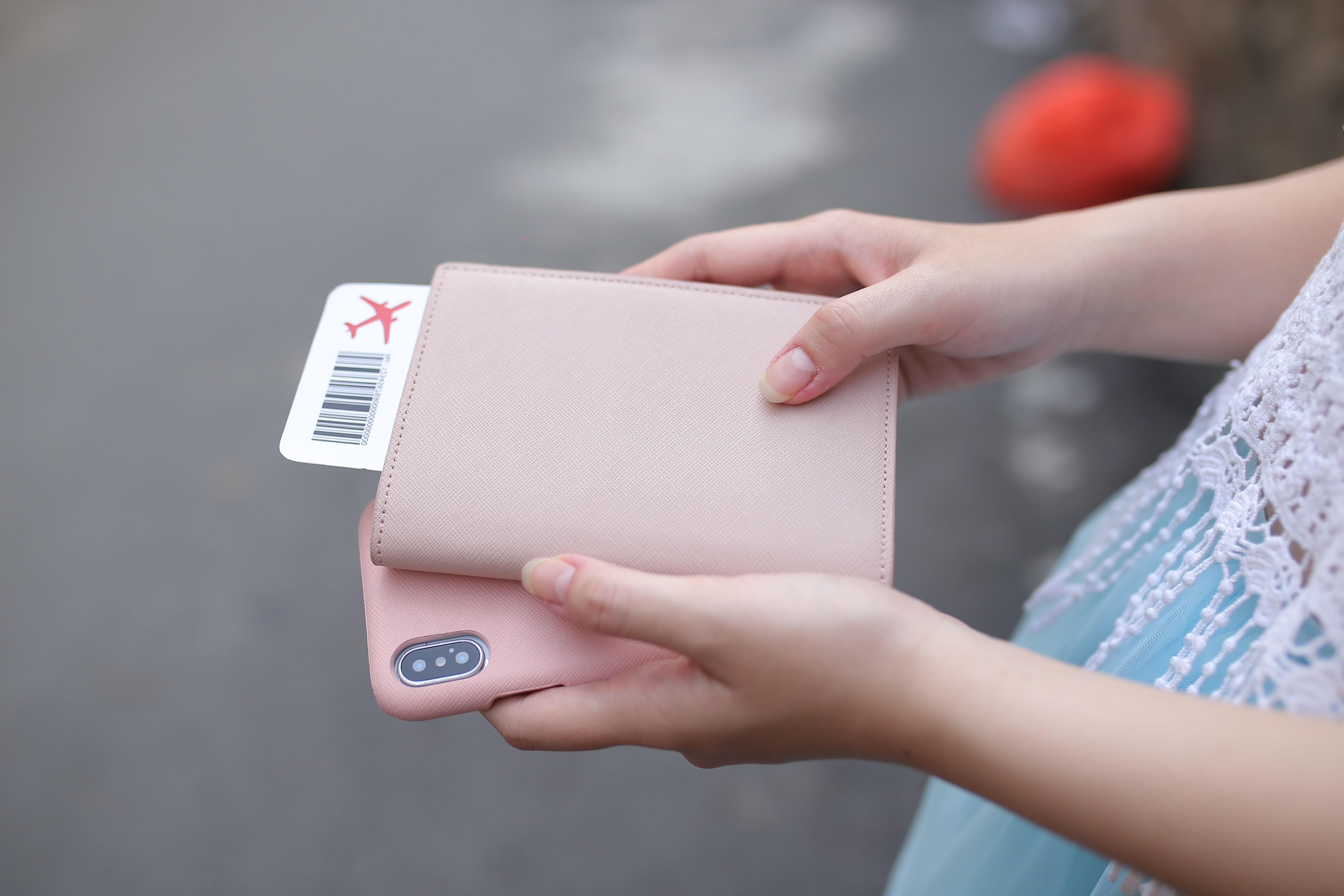 Una persona sostiene un pasaporte, una tarjeta de embarque y un teléfono